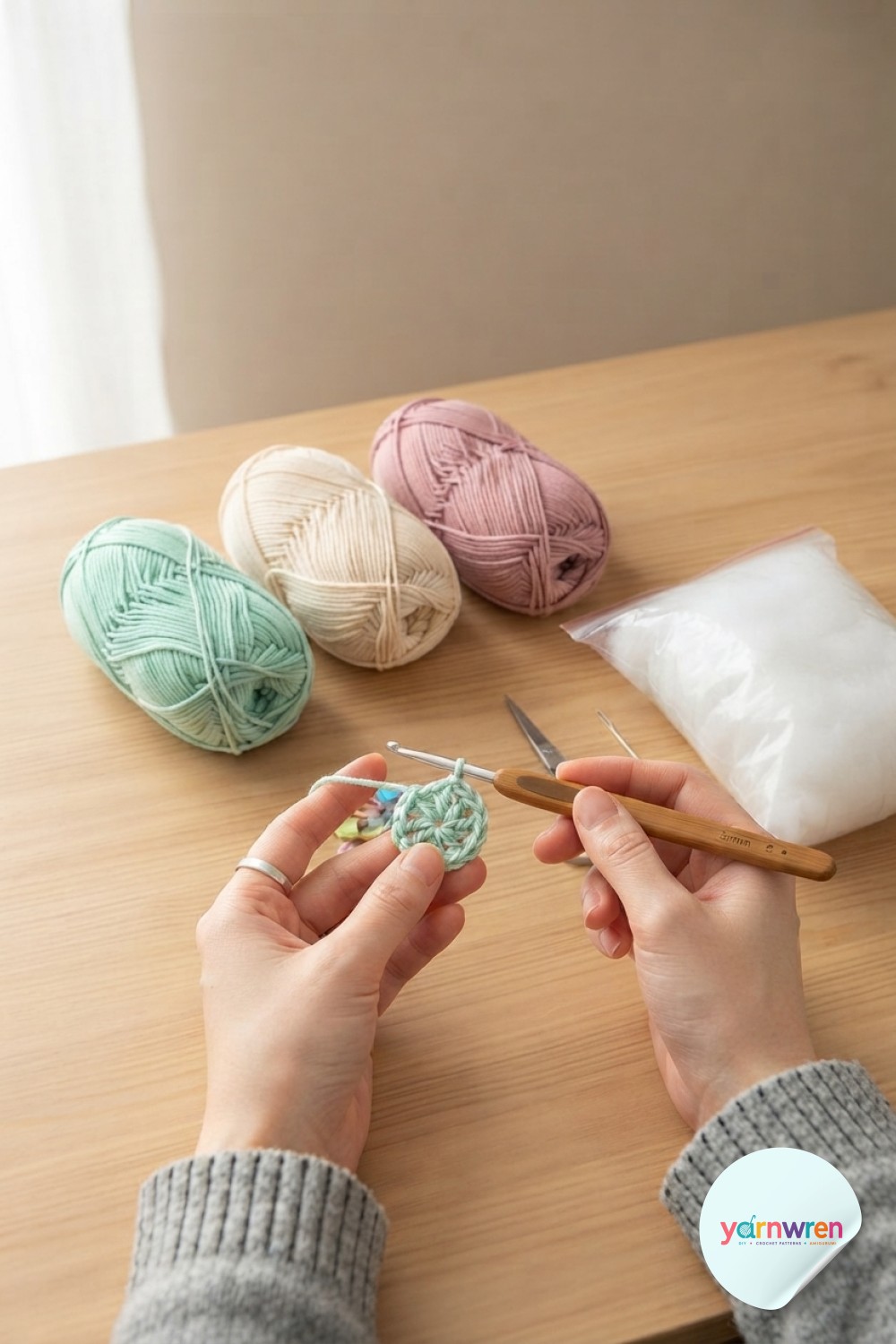 Hands starting a magic ring in mint yarn, the very first stitches of the crochet snake amigurumi pattern's tail.